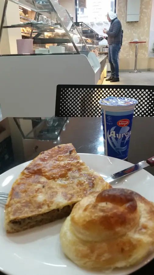 Burek mit Fleisch und gerollter Burek, dahinter Ayran und die Vitrine